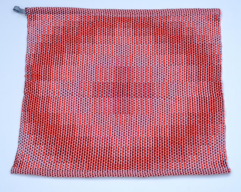 Handwoven red towel in cotton yarn using the corris effect shown from above