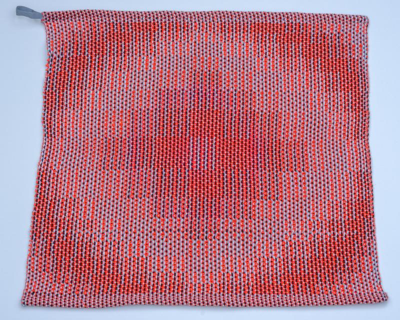 Handwoven red towel in cotton yarn using the corris effect shown from above using a slightly different pattern
