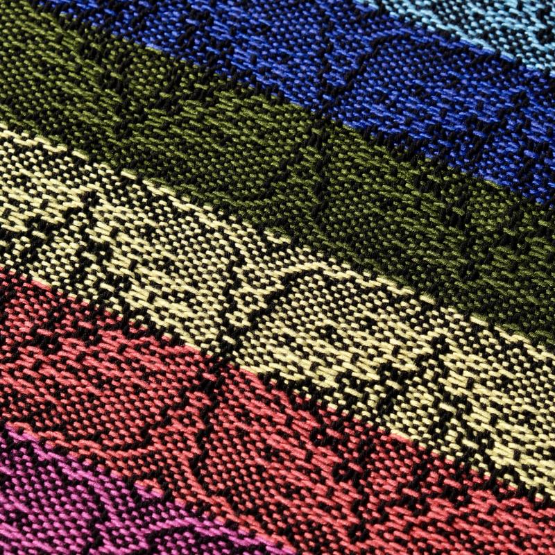 Close-up of a handwoven shawl in rainbow-colored bamboo yarn using advancing twill showing a star-shaped pattern
