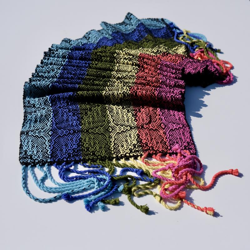 Handwoven shawl in rainbow-colored bamboo yarn using advancing twill folded in little waves showing three star-shaped motifs