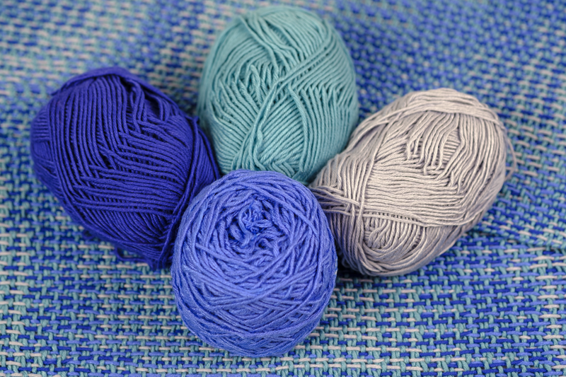 Four balls of bamboo viscose yarn in denim blue, dark blue, light blue and turquoise