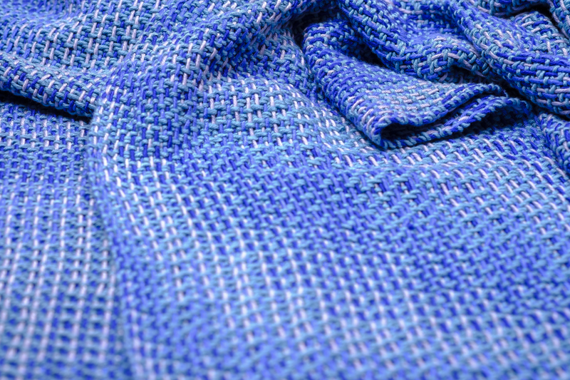 Close-up of a blue handwoven shawl with a straight twill network draped onto a table
