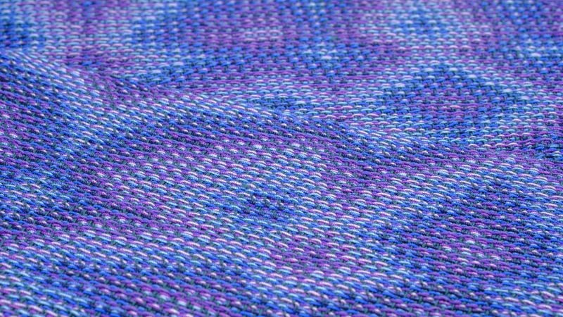 Shawl folded back onto itself showing both sides of a flower-like pattern in shades of blue and purple