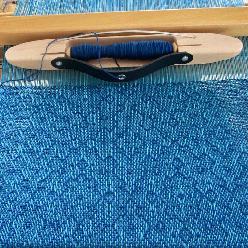 Shawl on the loom showing a shuttle