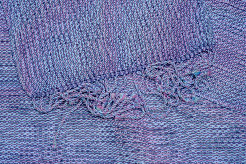 Close-up shot from above of a handwoven shawl in lyocell yarn using the Corris effect showing its twisted fringes
