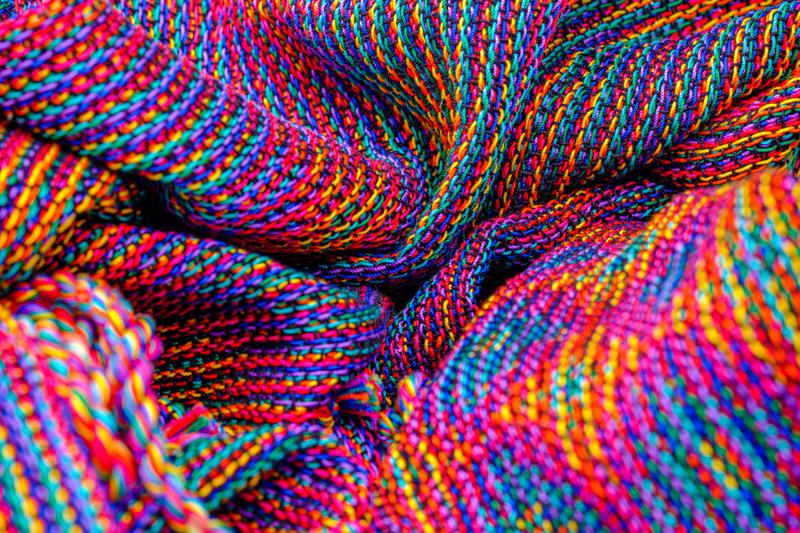 Close-up of two shawls in echo weave techniques using rainbow colors thrown in a bunch