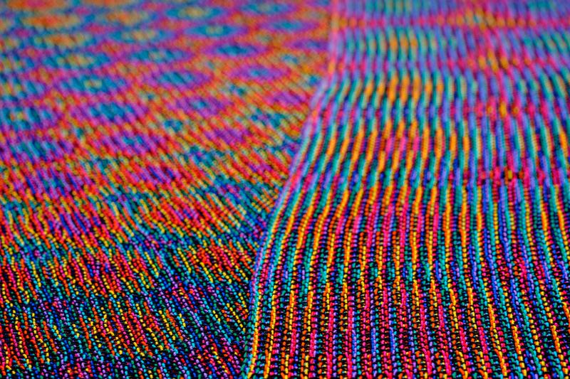 Close-up of two shawls in rainbow colors at an angle, showing echo-4 and echo-8 cloth equally