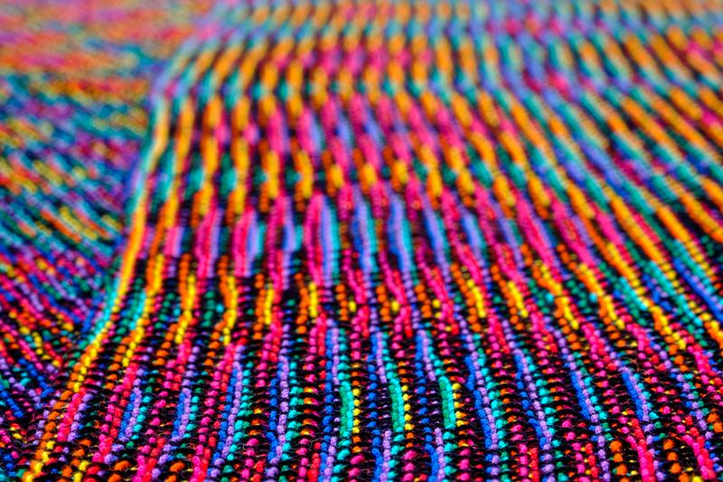 Close-up of two shawls in rainbow colors at an angle, mostly showing echo-8 cloth