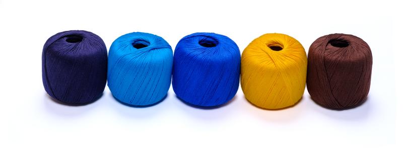 Five balls of yarn in shades of blue, yellow, and brown