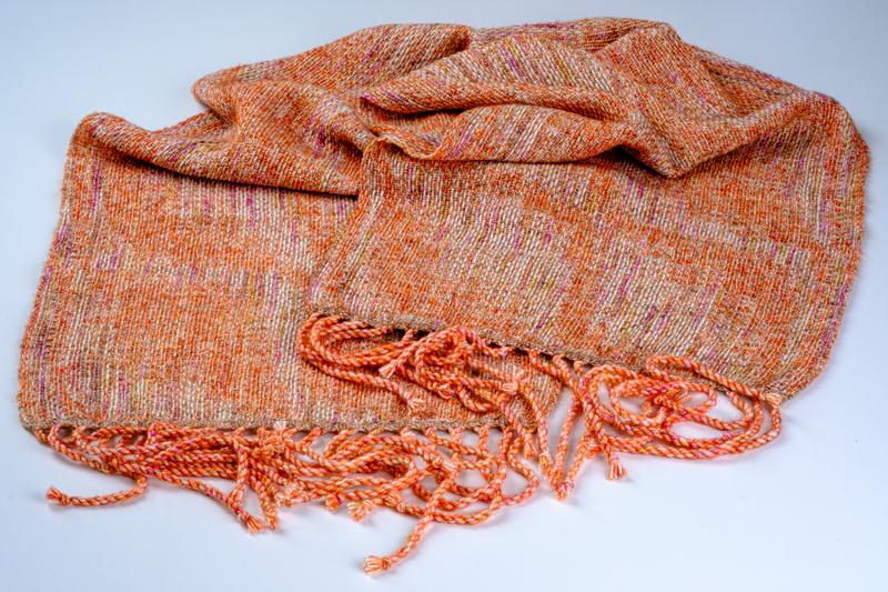 Overview of a handwoven shawl in reddish orange and beige